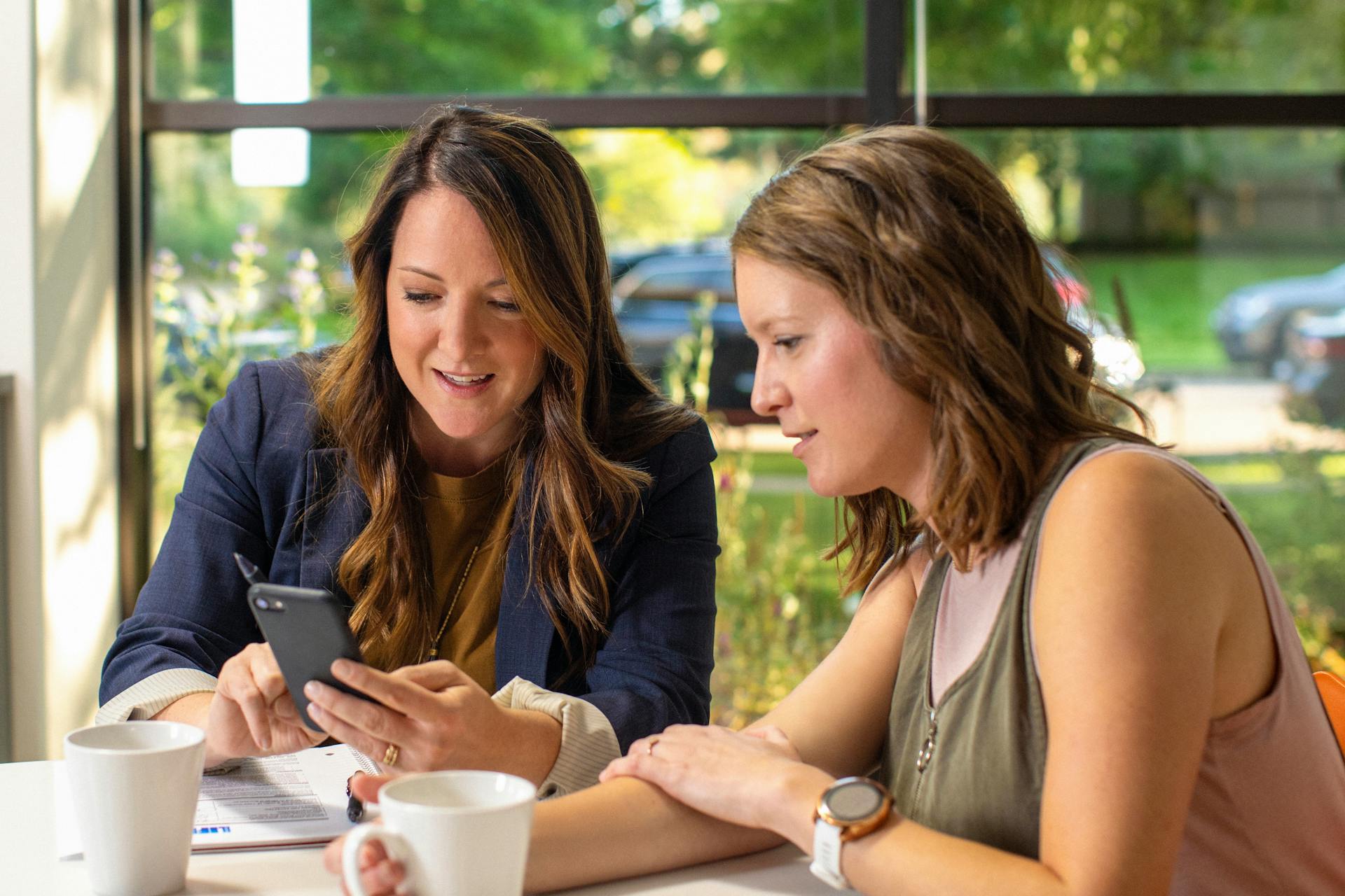 A businesswoman showing something to a client through her phone